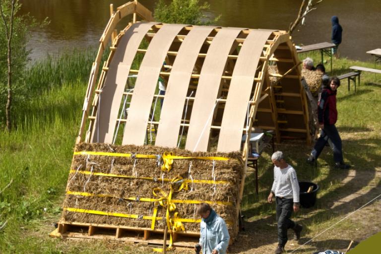 Die ersten vier Lagen der Strohbrücke werden mit Gurten verdichtet. | Foto: Hendrik Silbermann (ARTWORKs)