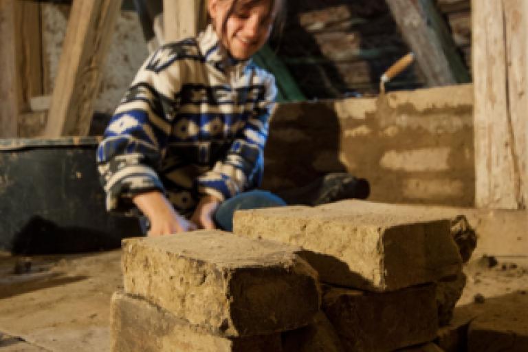 Eine Workcamp Teilnehmerin mauert mit alten Lehmsteinen
