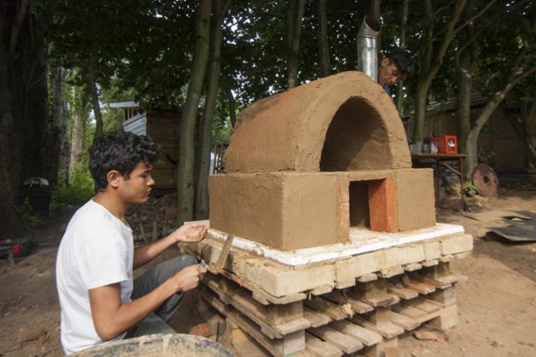 Ein Teilnehmer arbeitet am Lehmbackofen. | Foto: Hendrik Silbermann (ARTWORKs)