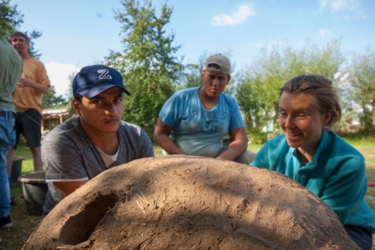 Workcamp-Teilnehmende bauen einen Lehmbackofen.