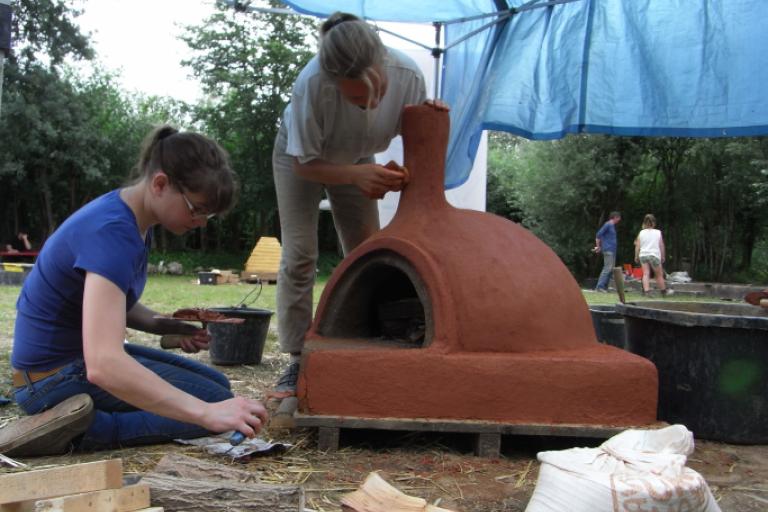 Workcamp-Teilnehmende bauen einen Lehmbackofen.