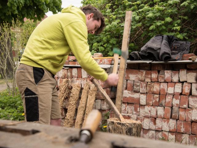 Staken vorbereiten und passgenau in das Gefach einsetzen | Foto: Hendrik Silbermann (ARTWORKs) Ein Teilnehmer des Workcamps passt die Länge der Staken an