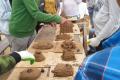 Workcamp-Teilnehmende bauen ein Modell eines Lehmbackofens. 