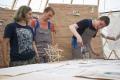 Drei junge Leute beim Bau eines brauchbaren Objekts für die Bildungsstätte für Lehmbau